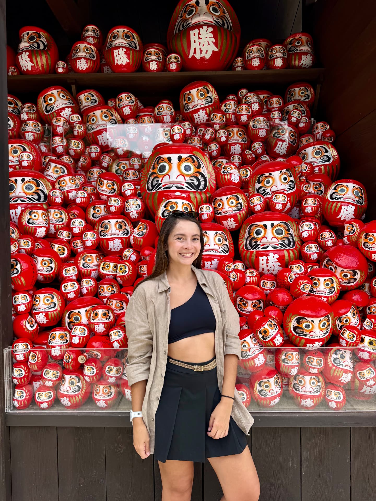 Viajera frente a muñecos daruma en el templo Katsuoji