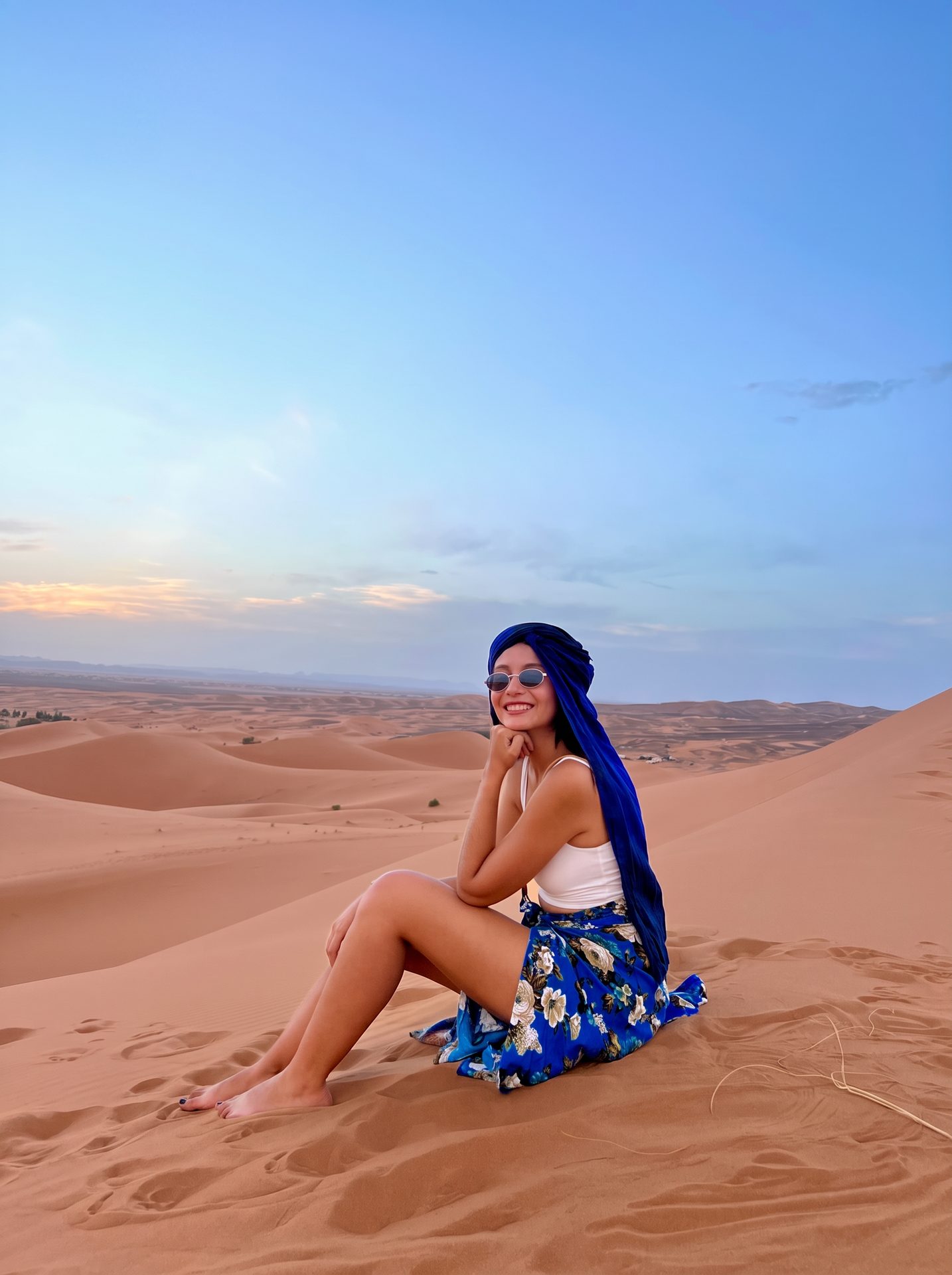 Viajera Weppa sentada sobre las dunas del Sahara al atardecer